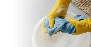 Hands squeezing out a cloth in a bucket of bubbly water